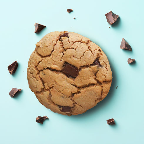 Top down view of the chocolate chunk UniCookie, The Regular Cookie, on a pastel blue backdrop.